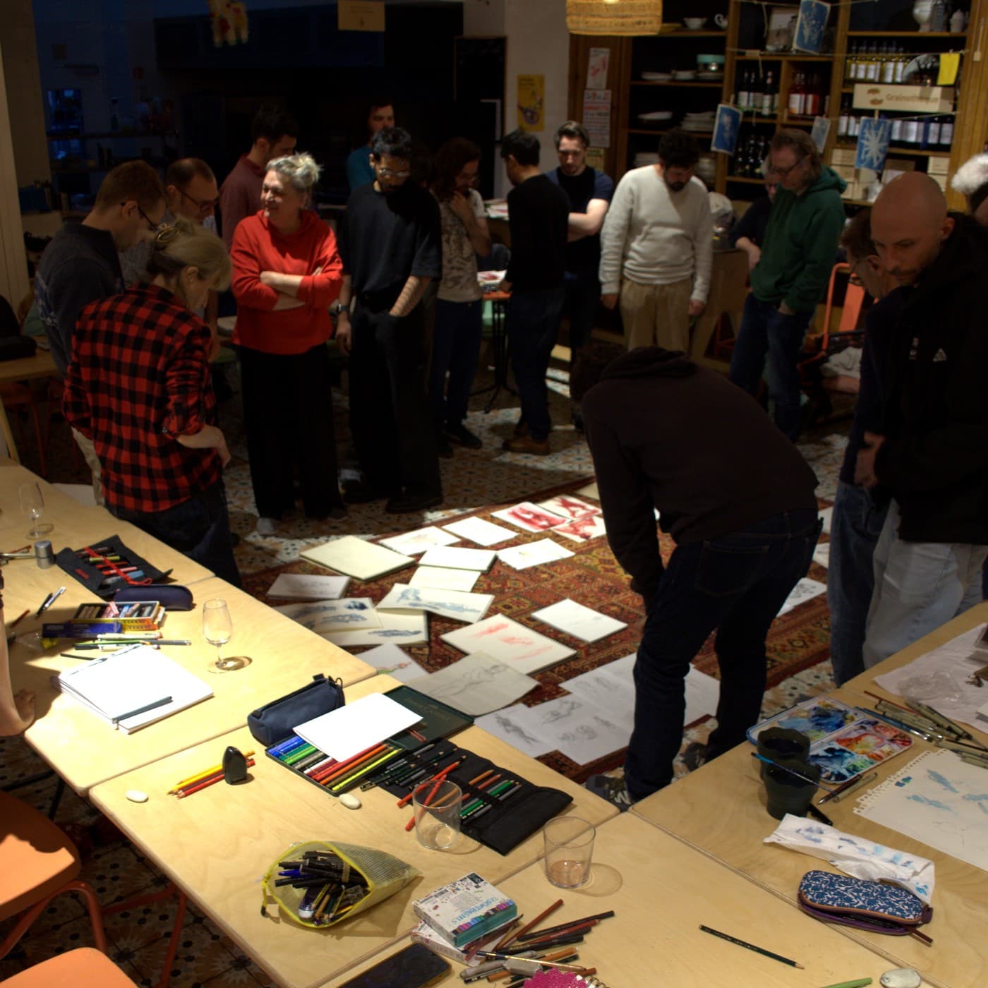 Des participants réunis autour des dessins étalés en fin d'atelier