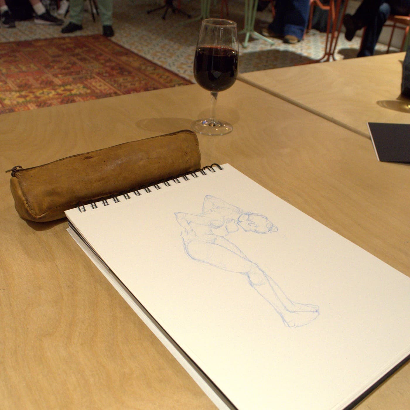 Un verre de vin rouge à côté d'un carnet de croquis